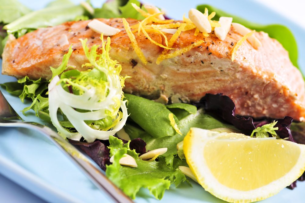 A plate of food with salmon and lemon.