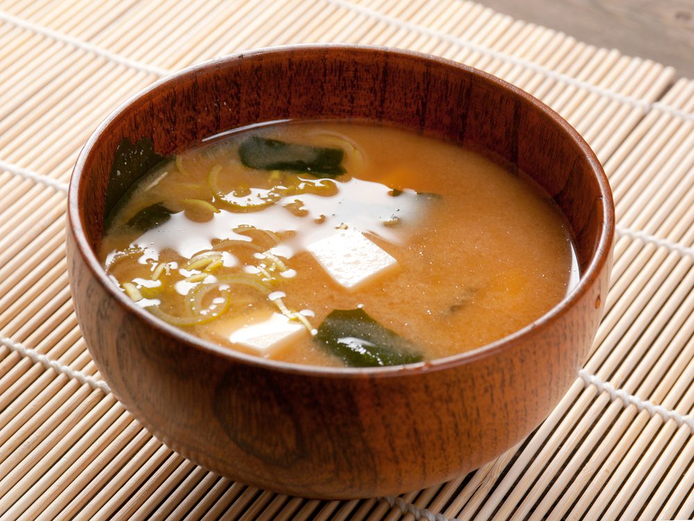 A bowl of soup with spinach and tofu.