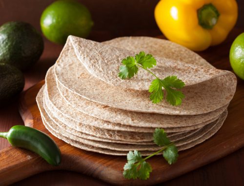 A stack of tortillas sitting on top of a wooden board.
