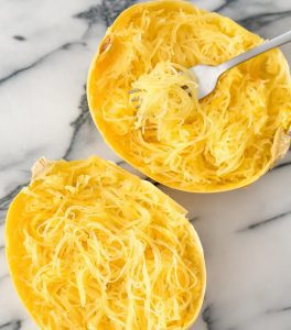 Two bowls of food on a table with one bowl full of noodles.