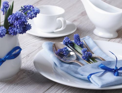 Blue hyacinth flowers on a table with silverware.