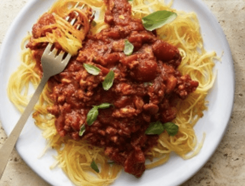 A plate of spaghetti and meat sauce with basil.