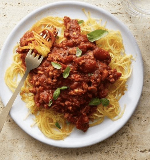 A plate of spaghetti and meat sauce with basil.