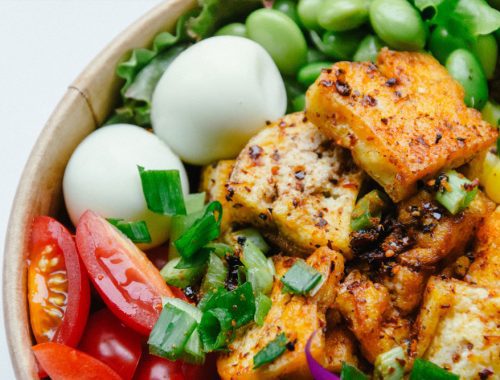 A bowl of tofu salad with vegetables and eggs.