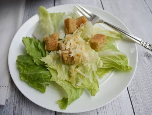 A plate of salad with croutons and lettuce.