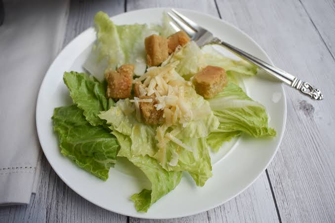 A plate of salad with croutons and lettuce.